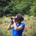 Eine Frau, die durch ein Fernglas schaut.