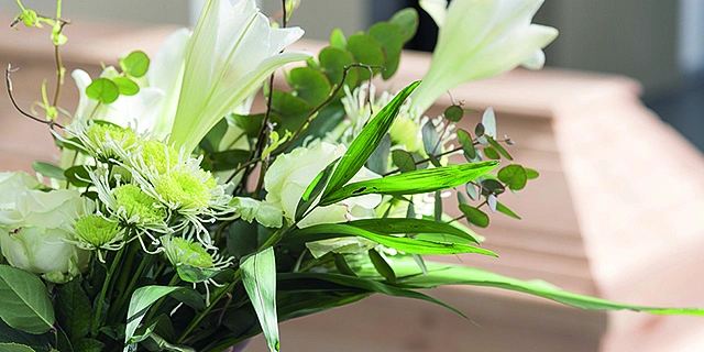 Blumen und ein Sarg im Hintergrund